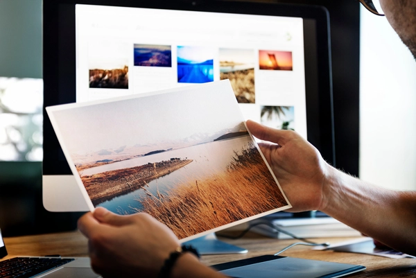 kuvitus-kuvat Mies katsoo valokuvaa. Taustalla tietokoneen näyttö.